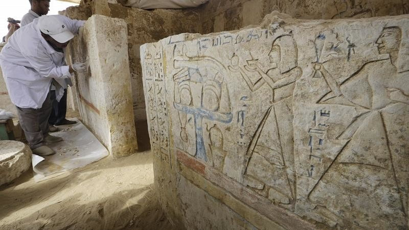 Des hommes dépoussièrent les hiéroglyphes inscrits sur des murs