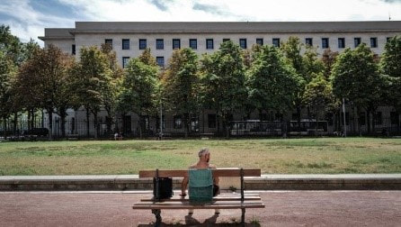 Une personne assise sur un banc devant un immeuble